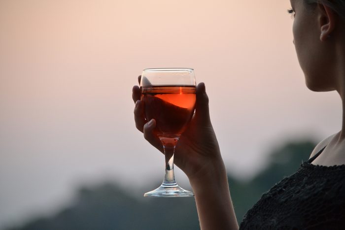 cropped shot of woman drinking wine at sunset