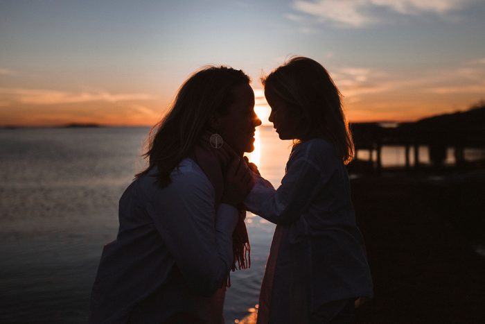 mother and daughter looking at each other with sunset in background