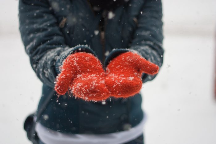 cropped shot of hands wearing mittens in the snow
