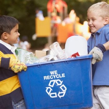 two little boys carrying a blue recycling bin