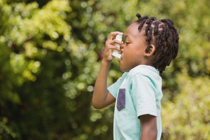 profile view of child using asthma inhaler
