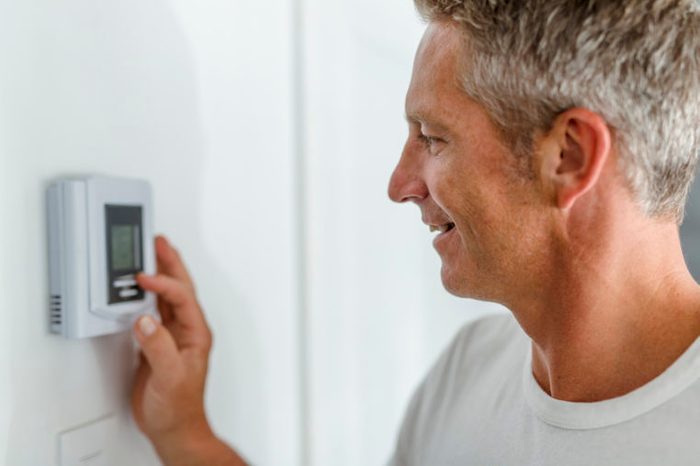 man adjusting the thermostat at home