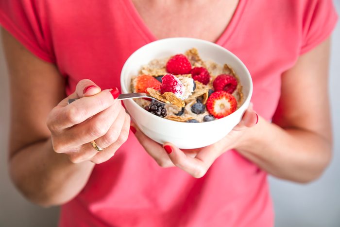 close up of woman holding bowl of yogurt breakfast