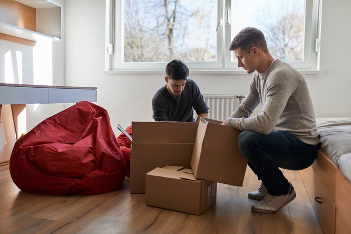 two young men unpacking boxes at college