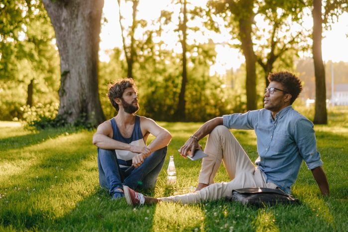 two men sitting in the park having a conversation