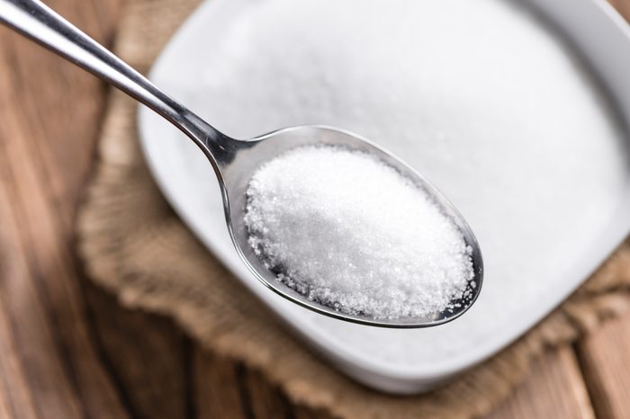 spoon full of granulated sugar over a bowl of sugar