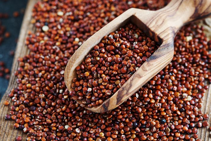 Seeds of red quinoa in wooden scoop