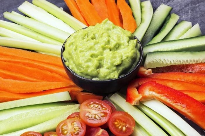 bowl of guacamole surrounded by sliced veggies