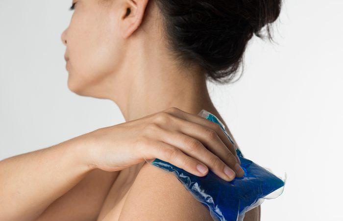 woman holding ice pack on shoulder
