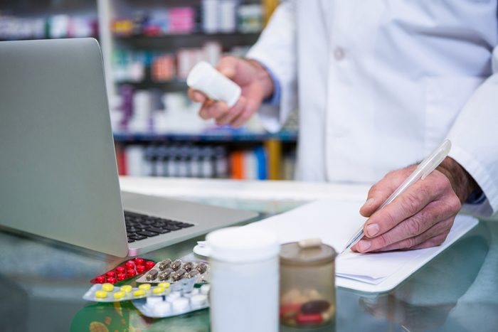 pharmacist with pill bottle on computer