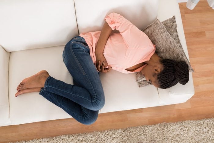 woman curled up in fetal position on a white couch