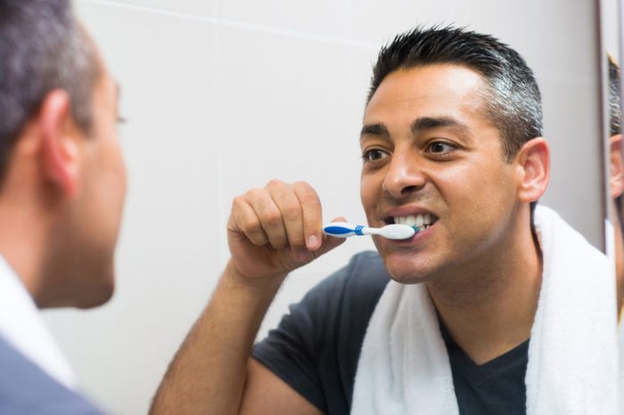 Man brushing his teeth while looking in the mirror 
