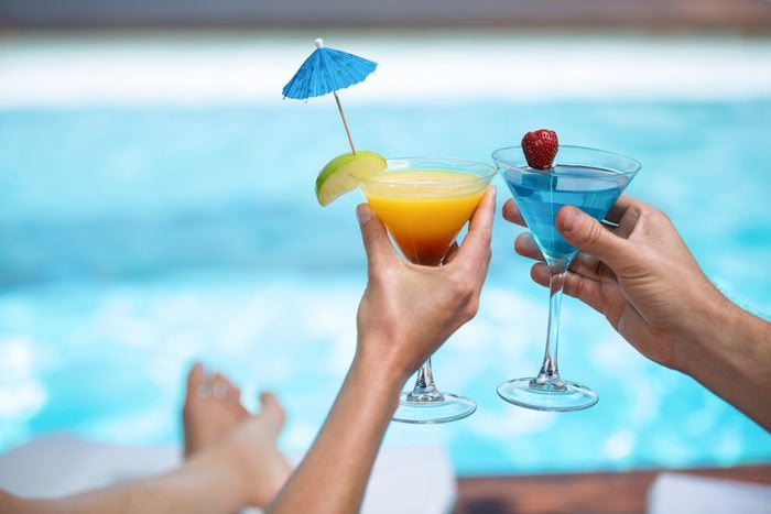 Hands of couple toasting martini glass near pool