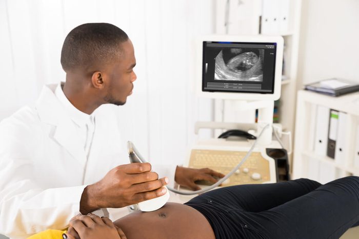 Man gynecologist or technician doing ultrasound on woman's stomach
