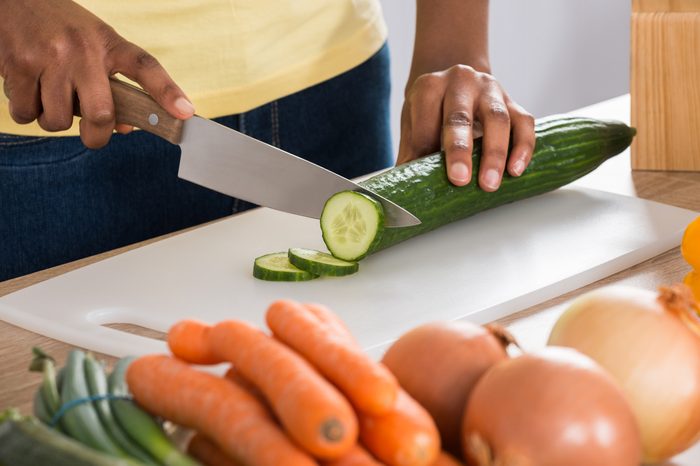 Woman's Hands Chopping cucumbers In Kitchen