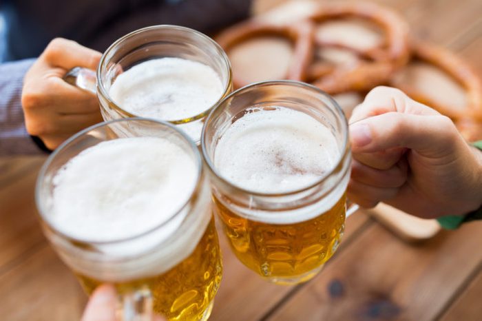 close-up of male hands clinking beer mugs in bar or pub