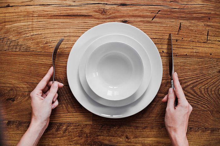 Healthy food theme: hands holding knife and fork on a plate
