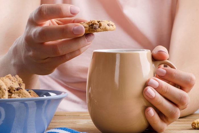 Female hands holding cup of tea and cookies