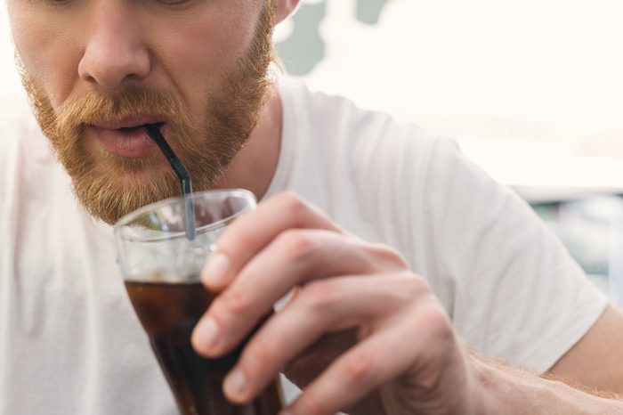 A bearded man drinking soda