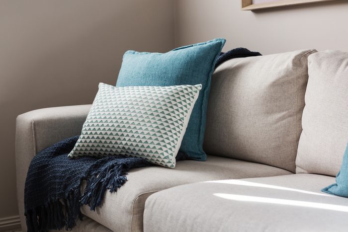 Close up of a fabric sofa with styled cushions and throw