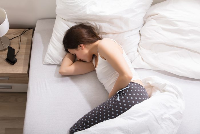woman in bed with stomach pain