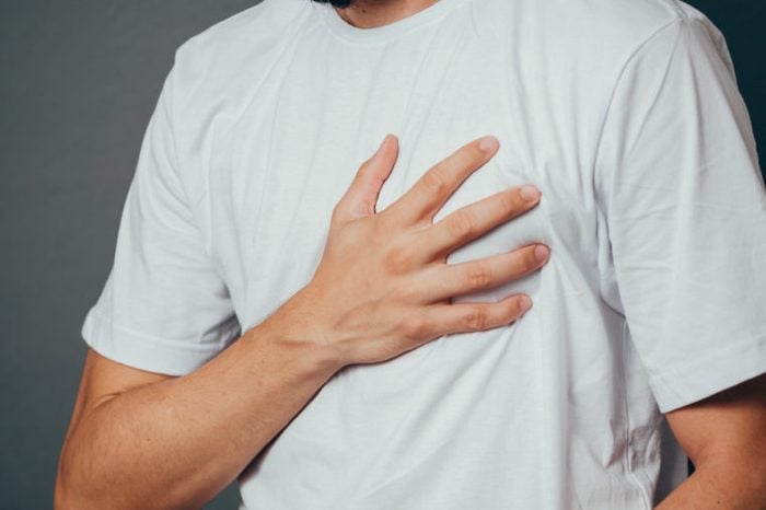 close up of man suffering from heart ache over gray background
