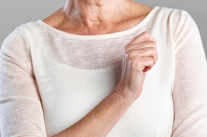 elderly woman with one arm crossed in front of her chest