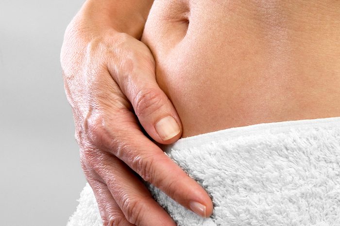 closeup of a person's abdomen wrapped in a towel, hand pressed against the stomach