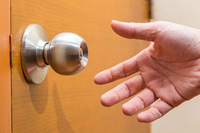 male hand reaching out to grab a door knob, good for coming home, home safety or intruder concept