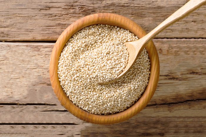 Raw quinoa close up in a wooden bowl on the table. top view from above horizontal background