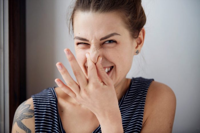 wincing woman pinches nose with fingers