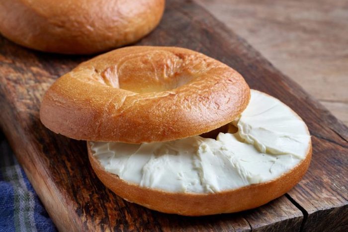 Bagel with cream cheese on wooden table