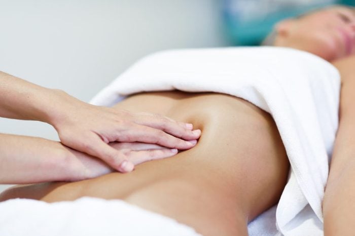 Therapist applying pressure on a woman's abdomen. 