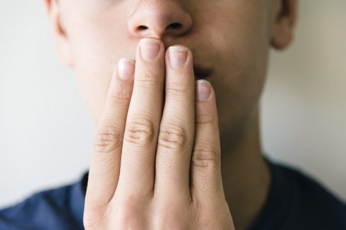 Teenage boy covering the mouth with his hand.