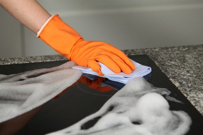Hand in protective glove cleaning a stove