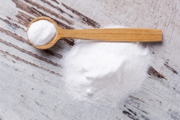 Magnesium powder on wooden spoon on white wooden textured background.