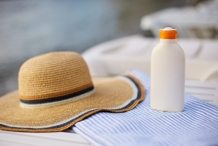 sunscreen bottle on beach towel and hat