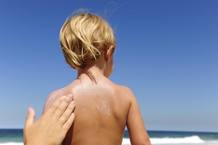 mother applying sunscreen on child's back
