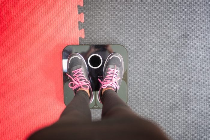 Woman standing on weigh scales at gym.
