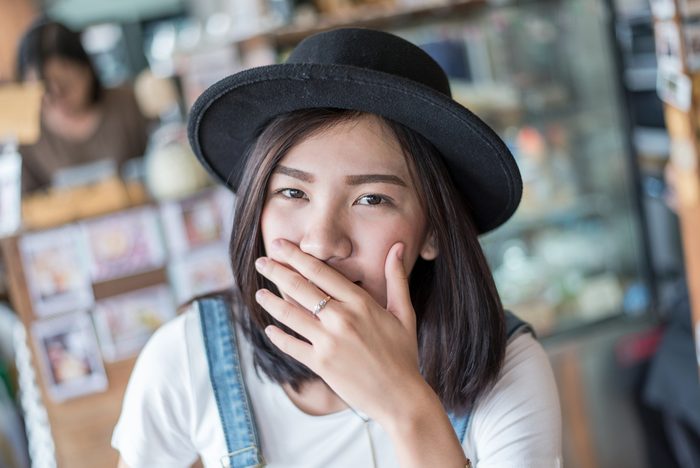 girl covers her mouth with her hands ,Asian shy girl with hat