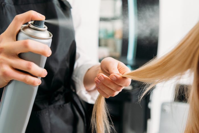 cropped image of hair stylist applying hair spray or dry shampoo