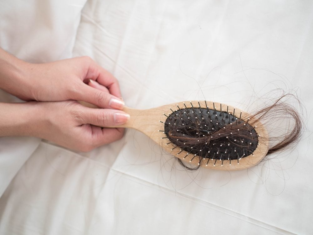 woman's hands holding brush with hair strands