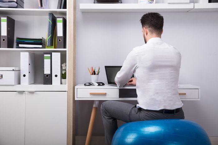 Businessman Sitting On Fitness Ball Using Laptop
