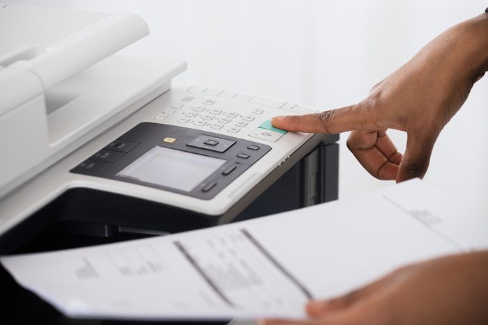 Close-up Of Young Businesswoman Hand Operating Printer In Office