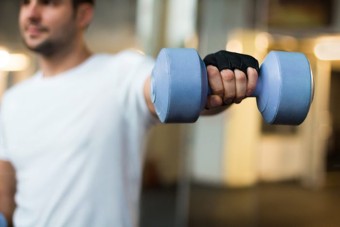sport and recreation concept - sporty men hands with light blue dumbbells 