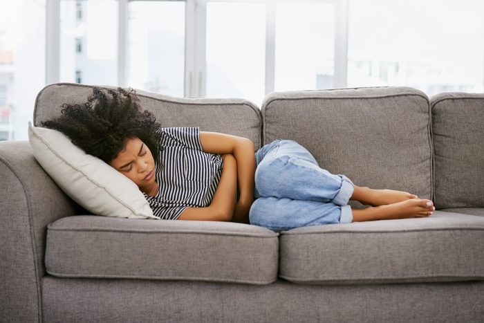 woman laying on couch with stomach ache