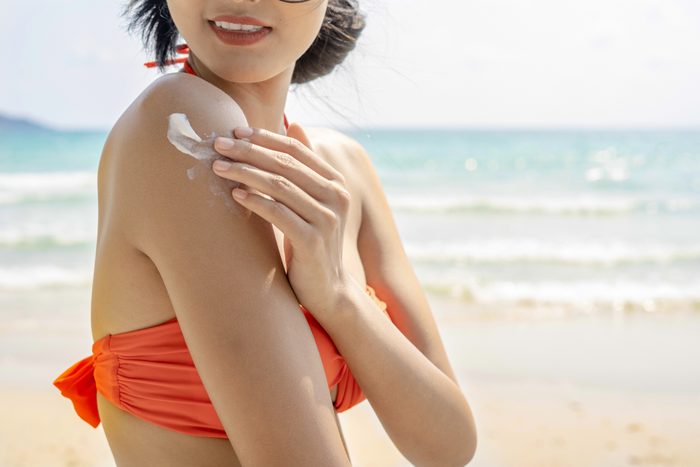 woman on the beach applying sunscreen to arm