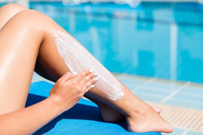 woman applying sunscreen to leg