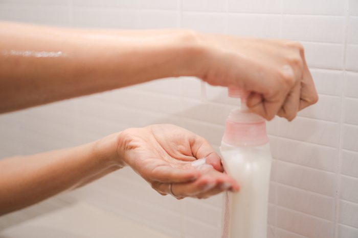 woman pumping shampoo into hand in the shower