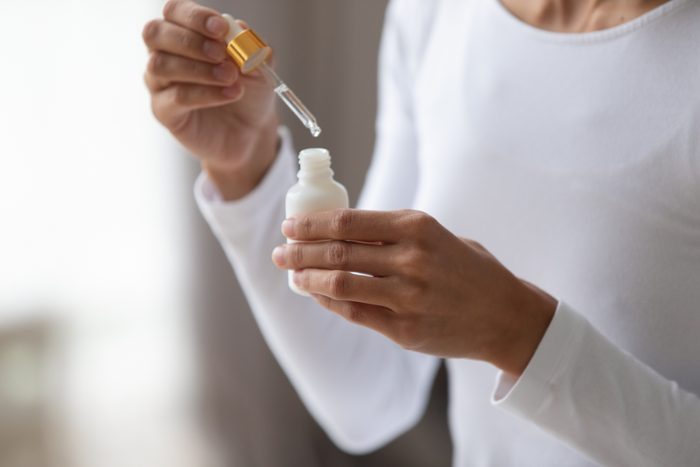 close up of woman holding serum bottle with pipette